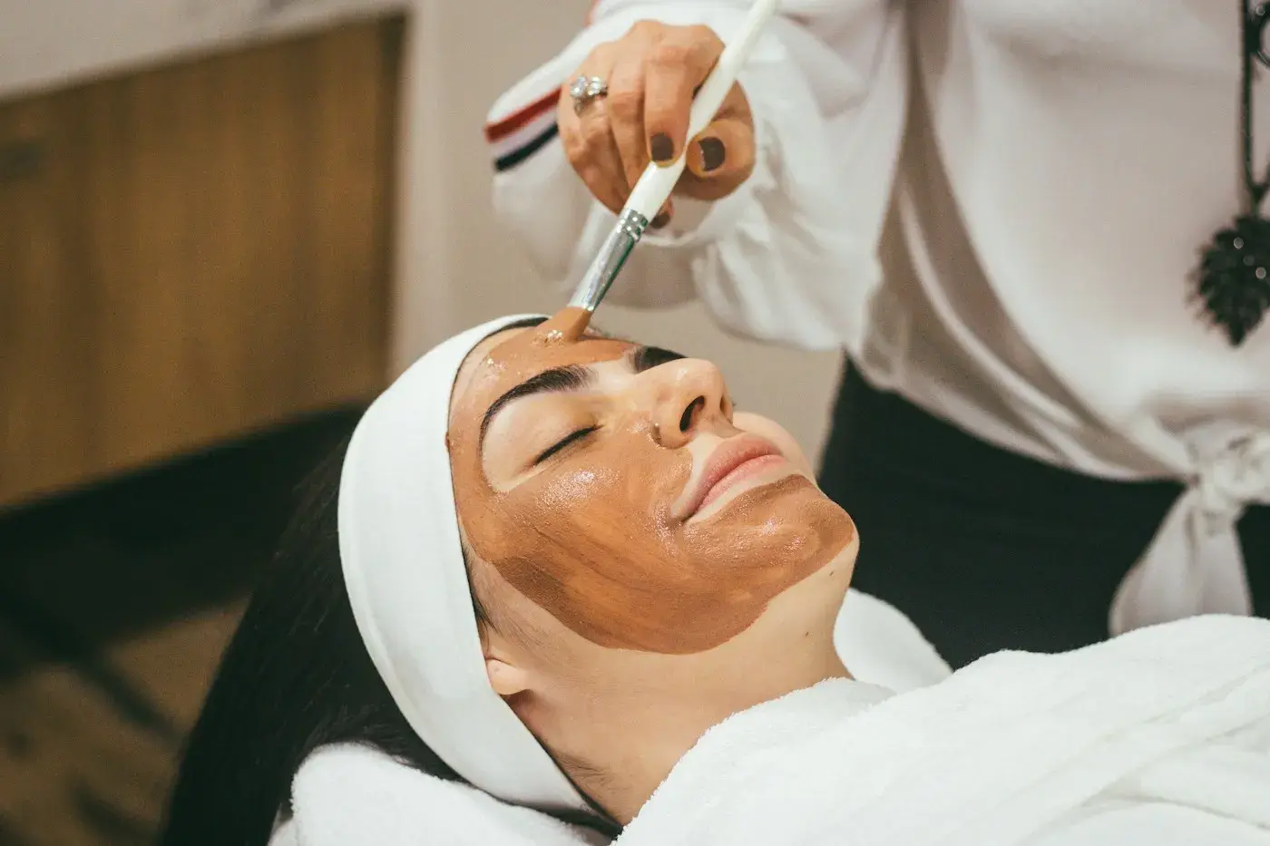 Clienta relajada recibiendo una mascarilla facial