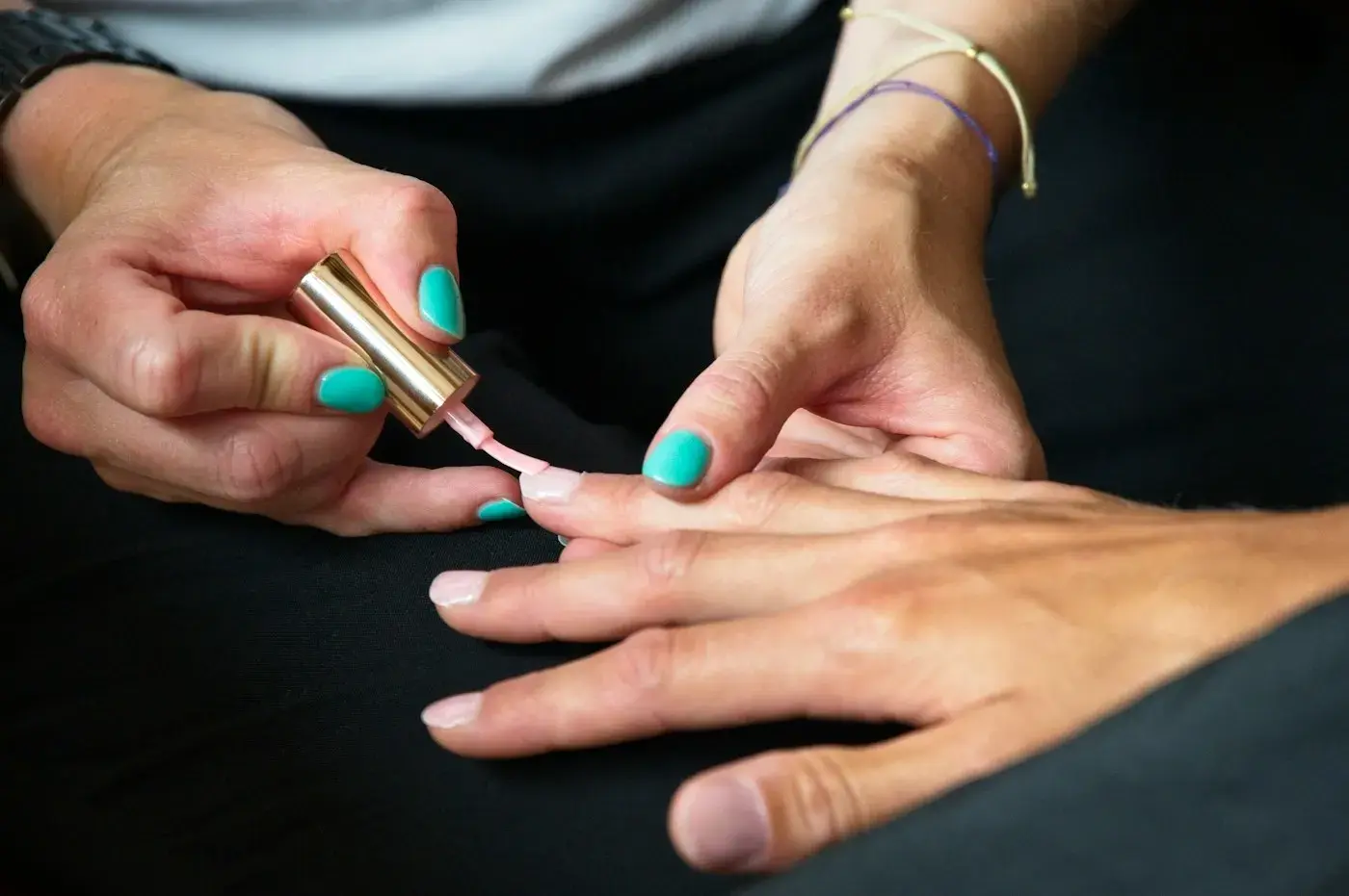 Manicurista aplicando esmalte turquesa